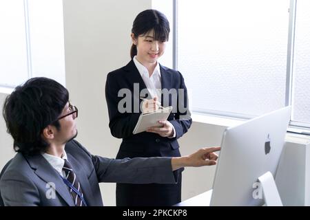 A new female employee jotting down notes after being taught her job by her supervisor. Stock Photo