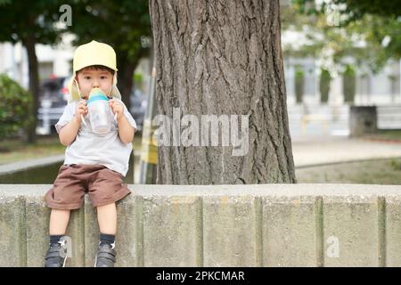 Child sitting in park drinking tea Stock Photo