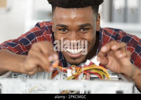 smiling man using multimeter while fixing pc Stock Photo