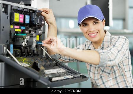 happy woman fixing a printer Stock Photo
