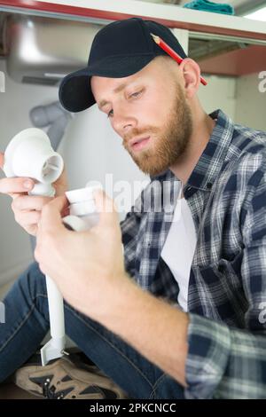 male plumber assembling waste pipes Stock Photo