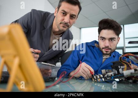happy electronic engineers examining digital multimeter Stock Photo