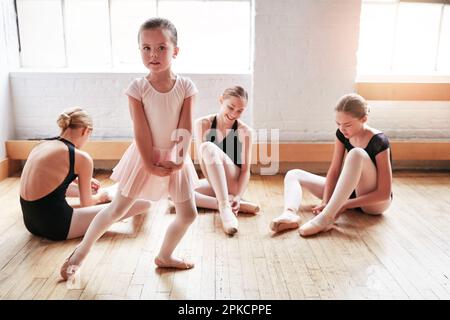 Dreams come true when you have courage to pursue them. an adorable little girl learning ballet with a group of older girls in a dance studio. Stock Photo