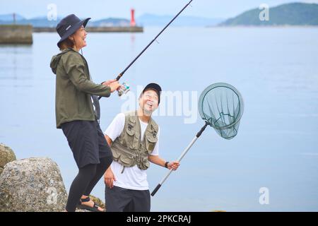 Image of Japanese Man With A Fishing Net Rod Fishing At Seashore