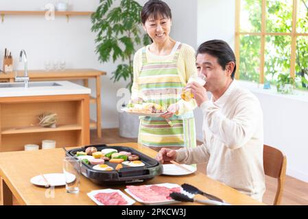 Middle-aged couple eating Yakiniku with draft beer Stock Photo