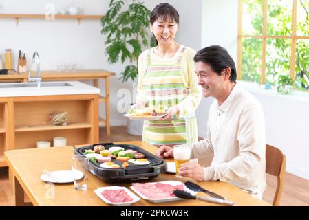 Middle-aged couple eating yakiniku with draft beer Stock Photo