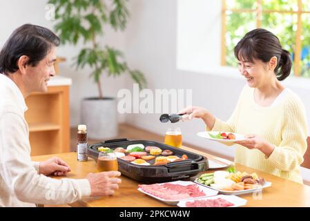 A middle-aged couple eating Yakiniku with draft beer Stock Photo
