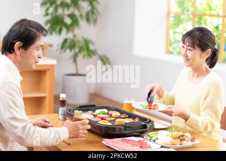 A middle-aged couple eating Yakiniku with draft beer Stock Photo