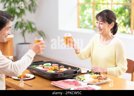A middle-aged couple eating Yakiniku with draft beer Stock Photo