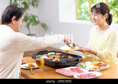 A middle-aged couple eating Yakiniku with draft beer Stock Photo