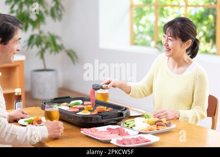 A middle-aged couple eating Yakiniku with draft beer Stock Photo