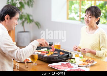 A middle-aged couple eating Yakiniku with draft beer Stock Photo