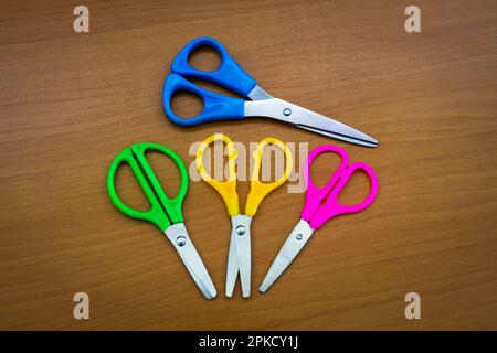 Multi-colored stationery scissors on the surface of the office table. Stock Photo