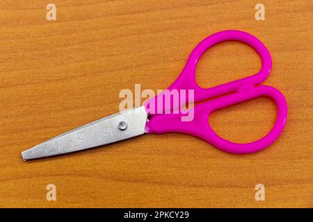 Purple stationery scissors on the surface of the office table. Stock Photo