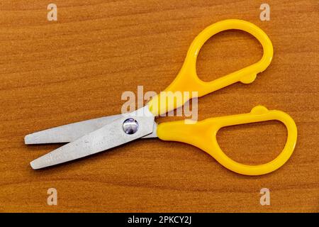 Yellow stationery scissors on the surface of the office table. Stock Photo