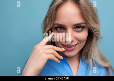 photo of shy cute casual young woman with smiling eyes on bright blue background Stock Photo