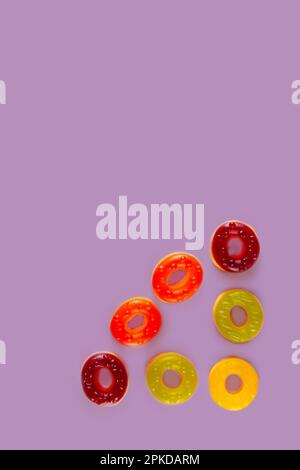 Triangle of round jelly candies at the corner of violet background. Colorful array of sweet circles Stock Photo