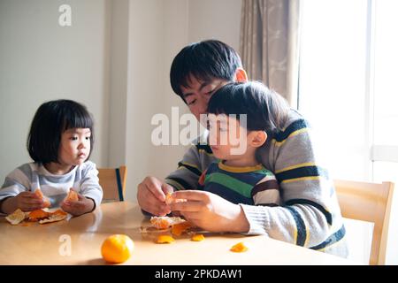 Parent and child peeling oranges Stock Photo