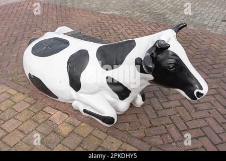 plastic cow with black and white spots standing outside on the street Stock Photo
