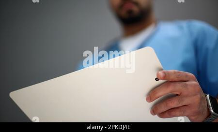 Portrait of a senior doctor holding notes against a gray background. close-up Stock Photo