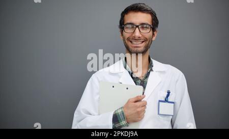 Studio portrait of a handsome mature male doctor holding medical records while standing against a dark background. Stock Photo