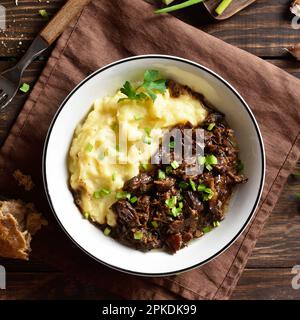 Slow cooked beef with mashed potatoes in bowl. Top view, flat lay Stock Photo