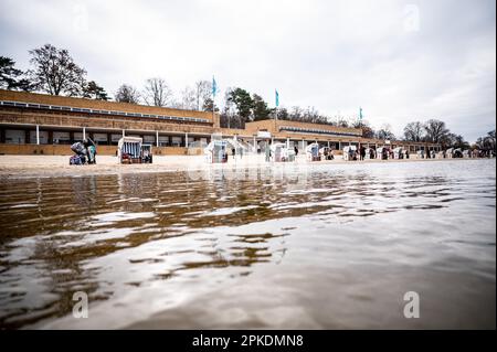 Berlin, Germany. 07th Apr, 2023. Visitors sit in beach chairs during the traditional bathing at Strandbad Wannsee on Good Friday in 8.4 degree cold water. A visit to the bath over the Easter holidays is always possible from 10:00 to 18:00 with free admission. Credit: Fabian Sommer/dpa/Alamy Live News Stock Photo