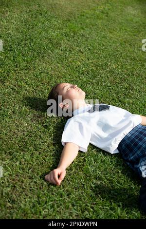 Schoolgirl in school uniform lying on the grass Stock Photo - Alamy