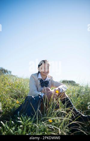 Schoolgirl in school uniform sitting on the lawn Stock Photo - Alamy