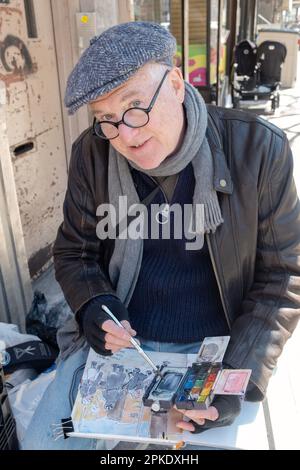 A Jewish man in a cap paints pictures of Jewish life on Lee avenue in Williamsburg, just before Passover 2023. In Brooklyn, New York. Stock Photo