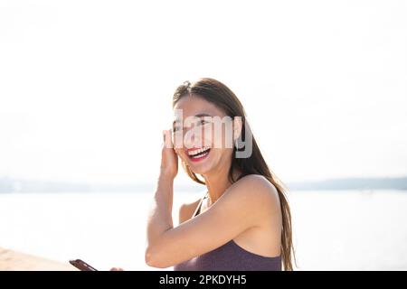 Woman in gym clothes holding her phone and laughing Stock Photo