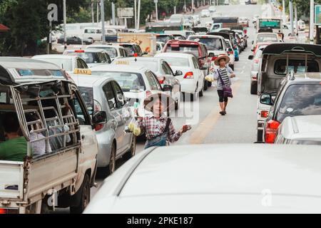 Yangon, Myanmar - March 25, 2023 : Myanmar man walking down on the street to sell food and drink in Yangon traffic jam. real local people lifestyle. Stock Photo