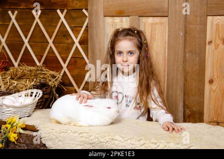 Farming and gardening for small children. Cheerful girl looking at rabbit. Stock Photo