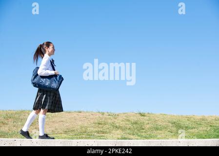 Schoolgirl in school uniform walking Stock Photo
