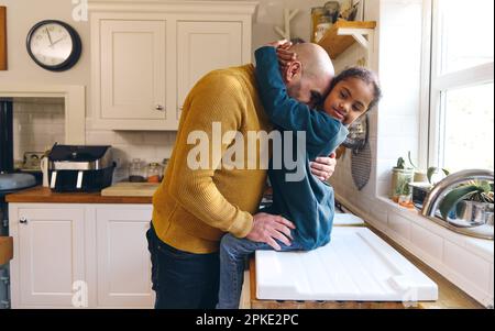 Loving father hugging son with Down syndrome sitting on counter Stock Photo