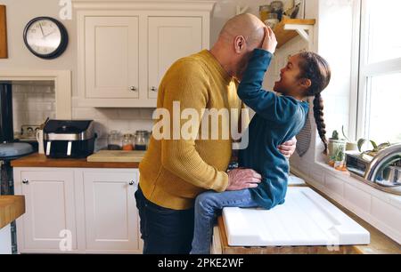 Father and playful son with Down syndrome smiling in kitchen Stock Photo