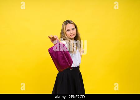 Little teenager girl with pencil case on a yellow background Stock Photo