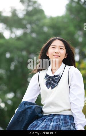 Female student sitting outside looking up Stock Photo
