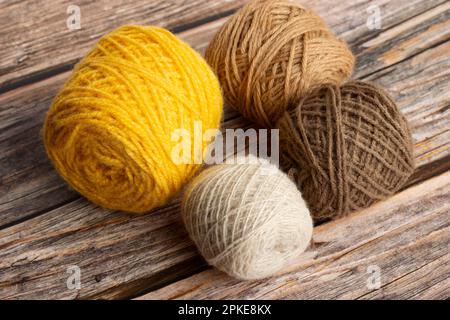 Brown and yellow wool spools on a wooden background Stock Photo