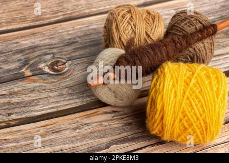 Brown and yellow wool spools and a spindle on a wooden background with copy space Stock Photo
