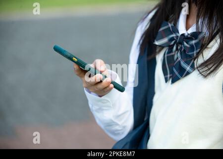 Female student in school uniform holding a cellphone Stock Photo