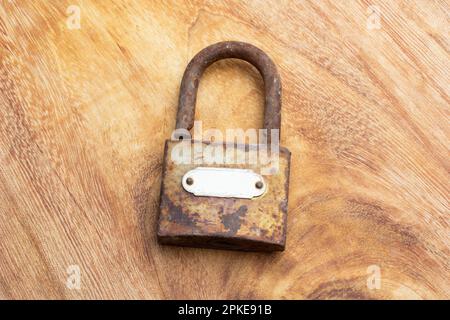 A rusty open padlock on a wooden table in a top view Stock Photo