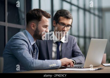 Two handsome businessmen working together on a project sitting Stock Photo