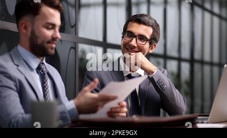 colleagues talking and sitting at table in creative agency Stock Photo