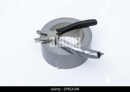 A pair of pliers on a roll of gray duct tape on a white surface Stock Photo