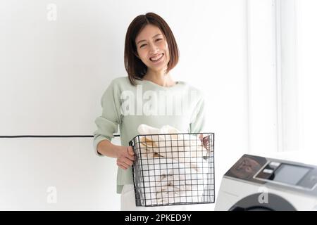 Woman laughing while holding a laundry basket Stock Photo