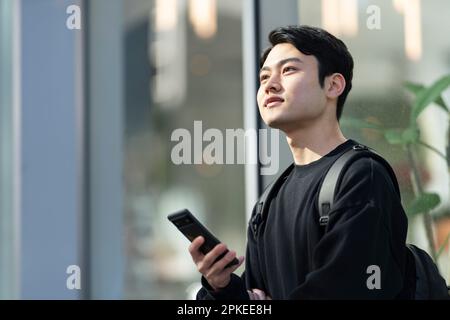 Man holding phone and looking far away Stock Photo