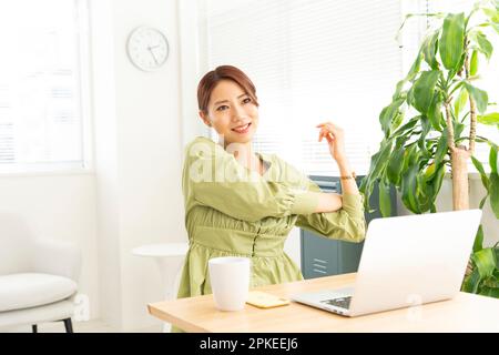 Woman stretching in front of computer Stock Photo