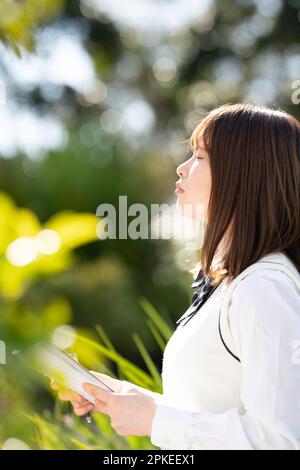 Schoolgirl in school uniform holding a notebook with her eyes closed Stock Photo