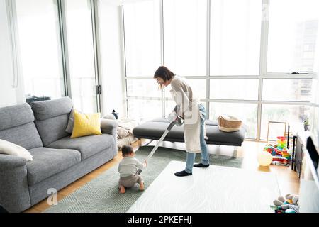 https://l450v.alamy.com/450v/2pkefhj/mother-vacuuming-at-home-with-baby-by-her-side-2pkefhj.jpg